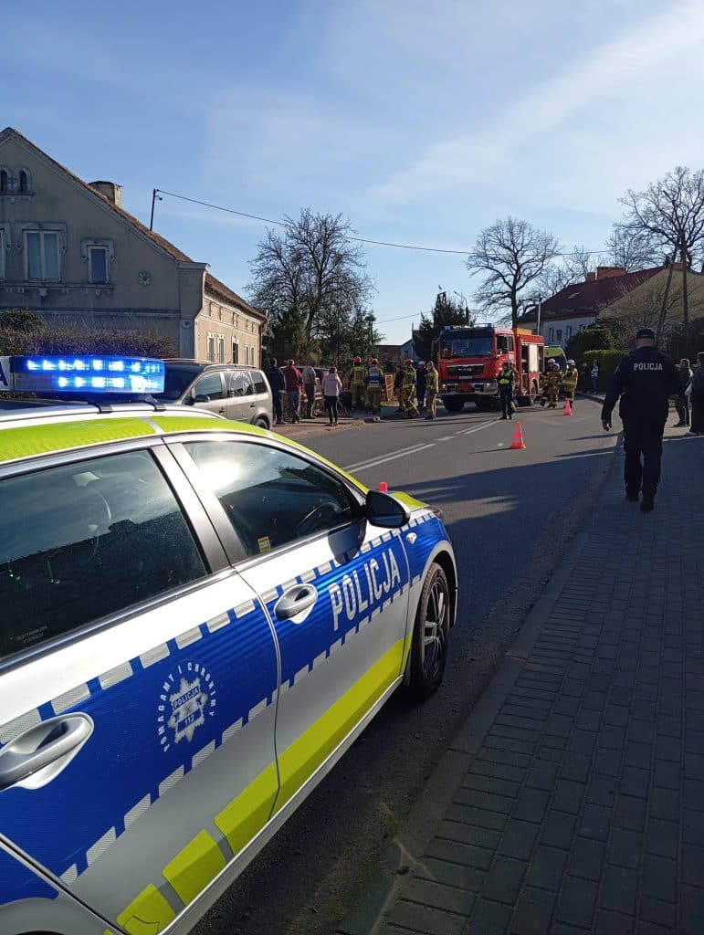 Widok na miejsce wypadku z udziałem samochodu i służb ratunkowych na drodze wojew&oacute;dzkiej.