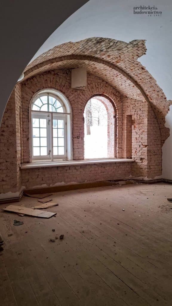 Widok wnętrza odrestaurowanego koszarowca z ceglaną architekturą i oknami, w trakcie prac remontowych.