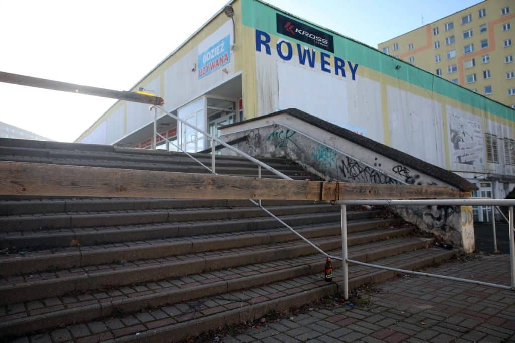Stare schody i graffiti na budynku handlowym przy Hali Urania w Olsztynie.