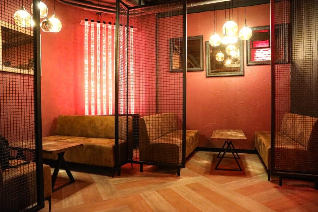 Wnętrze nowego klubu Dyskoteka Music Bar w Olsztynie, z czerwonymi ścianami, sofami i dekoracyjnym oświetleniem.