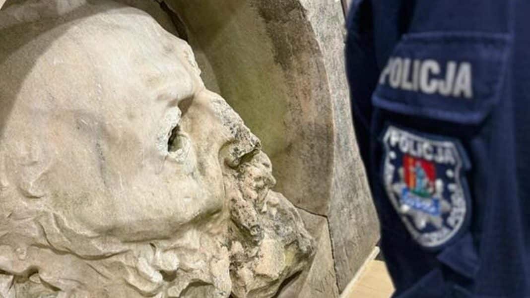 Policjant z Mazur przy odzyskanym dziele sztuki zniszczonym w wyniku kradzieży, widoczny fragment twarzy.