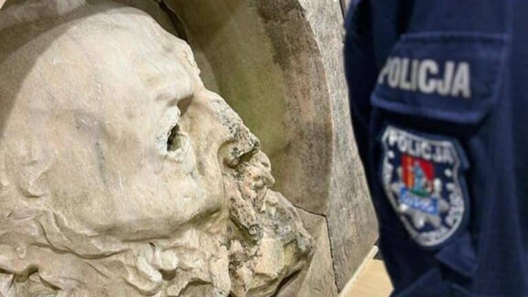 Policjant z Mazur przy odzyskanym dziele sztuki zniszczonym w wyniku kradzieży, widoczny fragment twarzy.