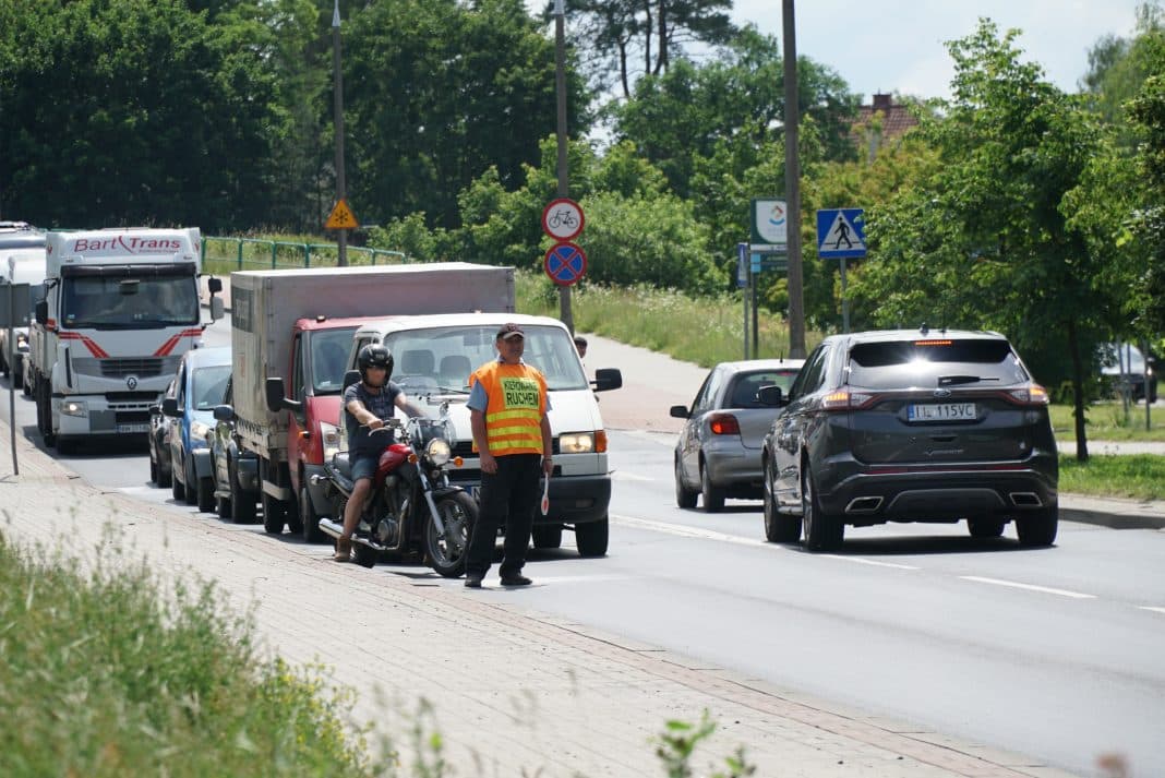 Kierowca i pracownik na ulicy w trakcie prac drogowych w Olsztynie, tworzą się korki.