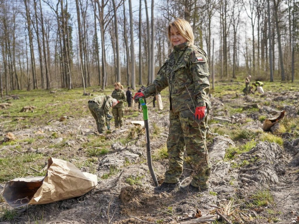 Strażnicy i młodzież sadzą drzewa w lesie na Mazurach podczas akcji z okazji Dnia Ziemi.