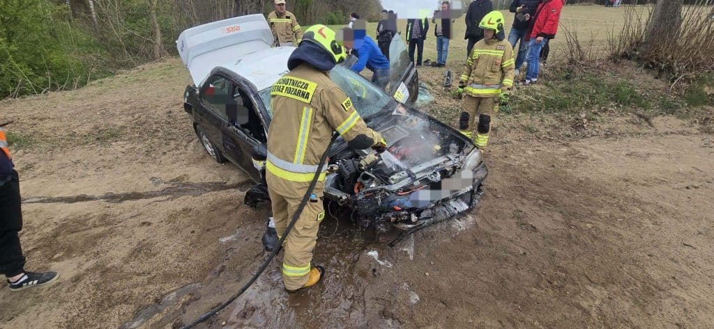 Strażacy gaszą pożar rozbitego samochodu po wypadku podczas rajdu w Warmii i Mazurach.