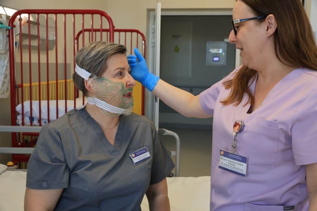 Lekarka sprawdza pacjentkę z maską chłodzącą na twarzy w szpitalu.