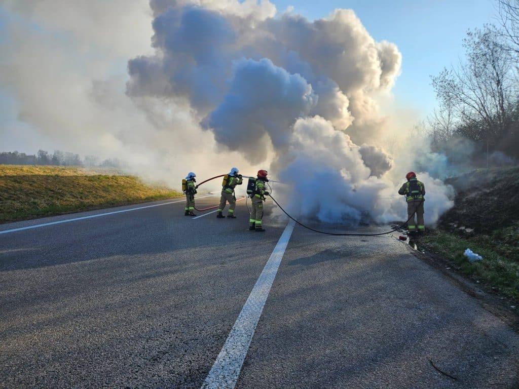 Strażacy gaszą pożar samochodu na drodze ekspresowej S22, unoszą się kłęby dymu.