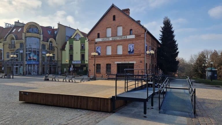 Nowa scena na olsztyńskiej star&oacute;wce, zbudowana z drewna, na tle historycznych budynk&oacute;w i pomnik&oacute;w.