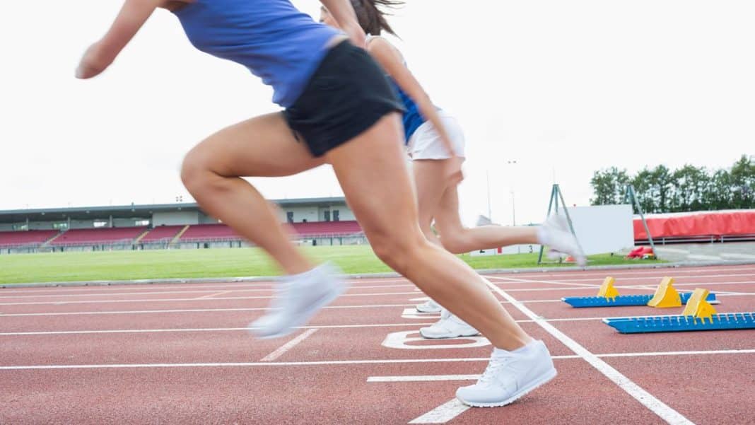 Biegacze startują z linii startu na stadionie, przygotowując się do wyścigu.