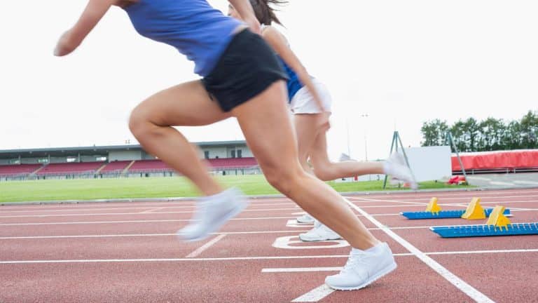 Biegacze startują z linii startu na stadionie, przygotowując się do wyścigu.