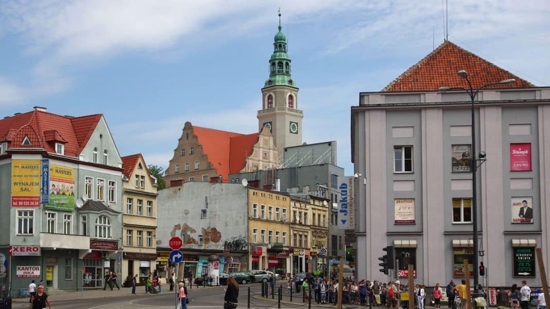 Widok na centrum Olsztyna z nowoczesnym biurowcem i historyczną wieżą w tle.