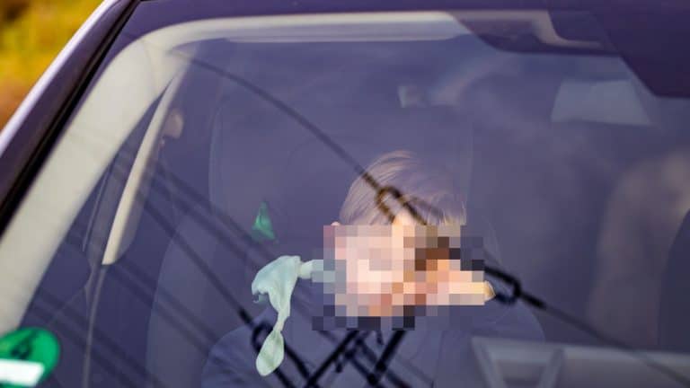 Dziecko siedzi na przednim fotelu samochodu, widoczny jest kierowca, policja zatrzymała pojazd.