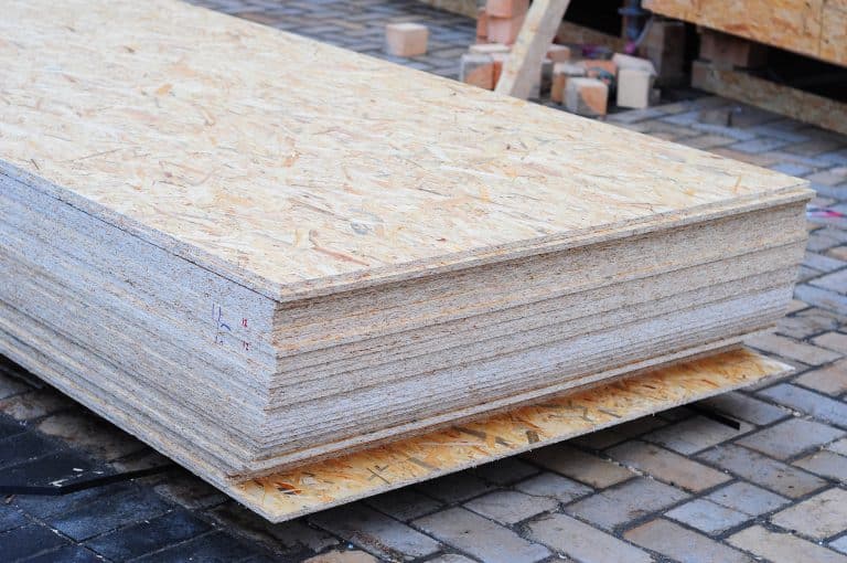 Stos arkuszy płyty pilśniowej na placu budowy, gotowe do obr&oacute;bki.