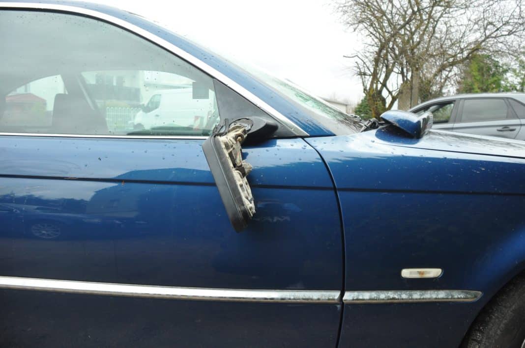 Uszkodzony samoch&oacute;d z wyrwanym lusterkiem bocznym, na parkingu w Ełku.