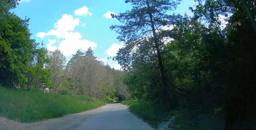 Wąska, odnowiona droga w otoczeniu zieleni i drzew, zakończona modernizacją w miejscowości Ruś.