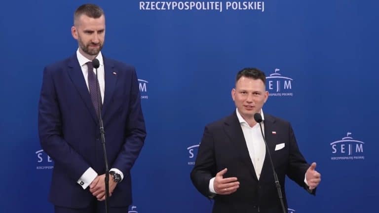 Dw&oacute;ch mężczyzn w garniturach podczas debaty w studiu z niebieskim tłem z napisem SEJM.