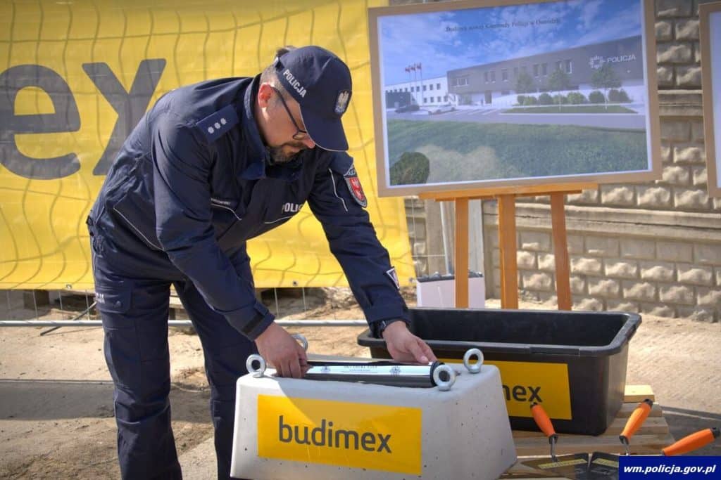 Policjant montuje elementy konstrukcyjne na placu budowy nowej komendy w Ostr&oacute;dzie.