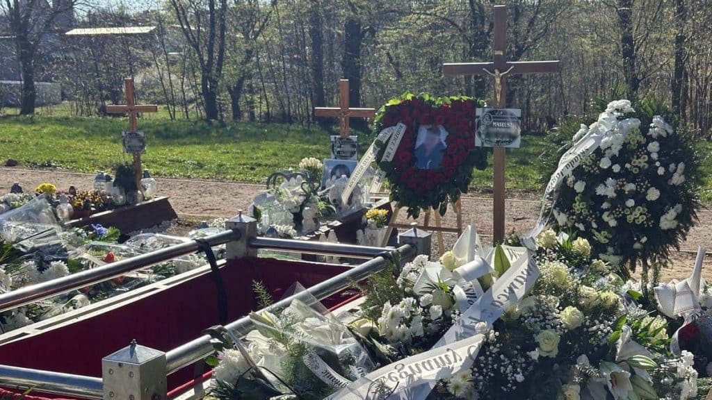 Widok na kwiaty i wieńce pogrzebowe przy grobie młodego chłopca podczas uroczystości w Suszu.