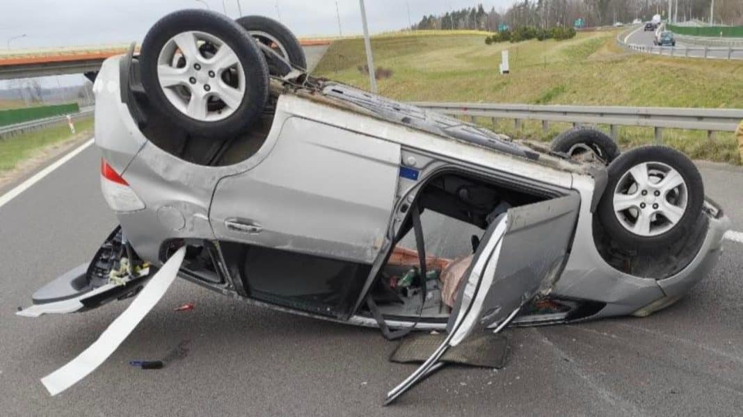 Rozbity samoch&oacute;d leży na dachu na drodze, w pobliżu barier energochłonnych, wypadek na S7.