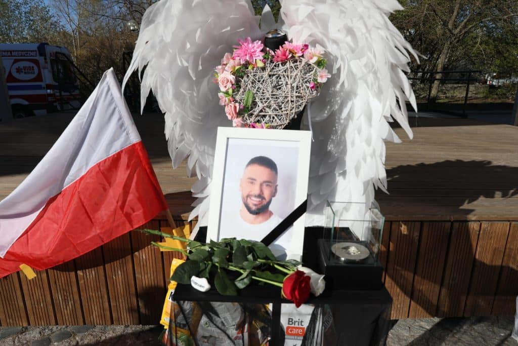 Na Targu Rybnym w Olsztynie ustawiono zdjęcie zmarłego Łukasza Litewki, obok kwiaty, flagi i symboliczne serce.