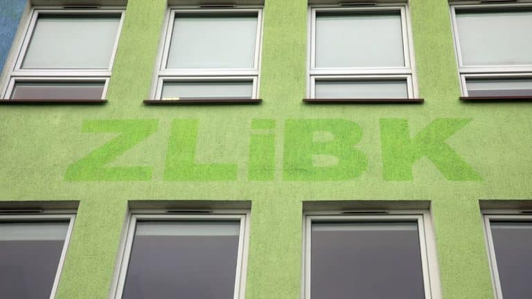 Zielona ściana budynku z napisem 'ZL&Iacute;BK' na tle kilku okien.