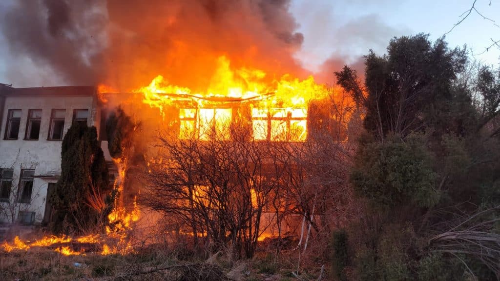 Pożar pustostanu przy ul. Junak&oacute;w w Elblągu, ogień i dym unoszą się nad budynkiem.