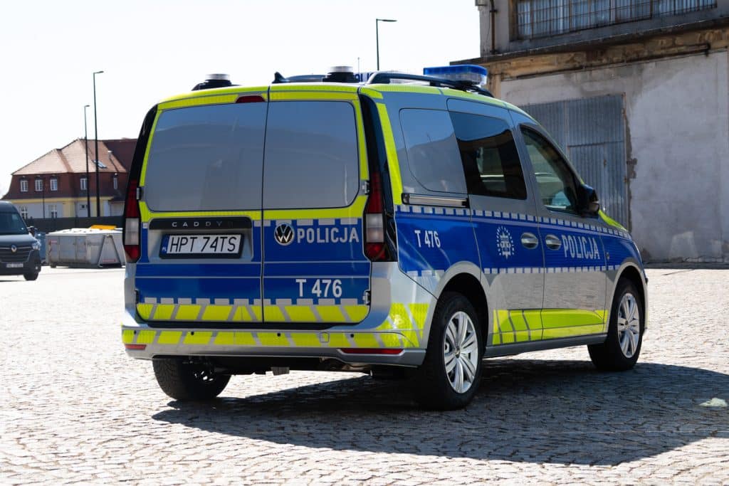 Nowoczesny radiow&oacute;z policyjny na ulicy na Mazurach, w barwach ż&oacute;łto-niebieskich, z oznaczeniem 'Policja'.