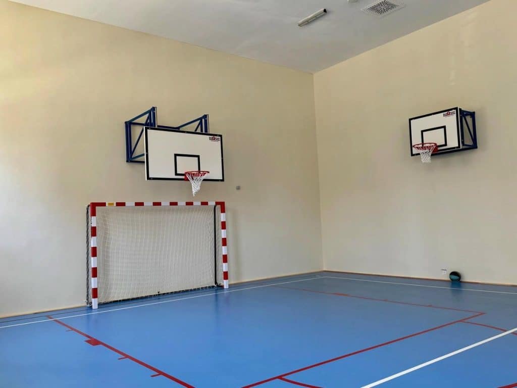 Nowoczesna hala sportowa w szkole podstawowej z boiskami do gry w koszyk&oacute;wkę i piłkę ręczną.