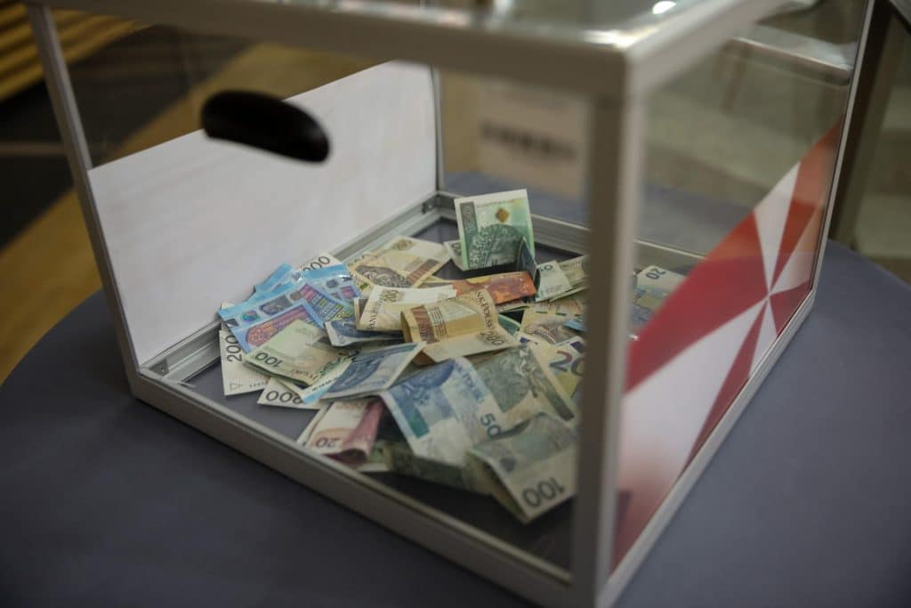 Skrzynka z banknotami na stole, symbolizująca zbi&oacute;rkę na cele charytatywne podczas wydarzenia.