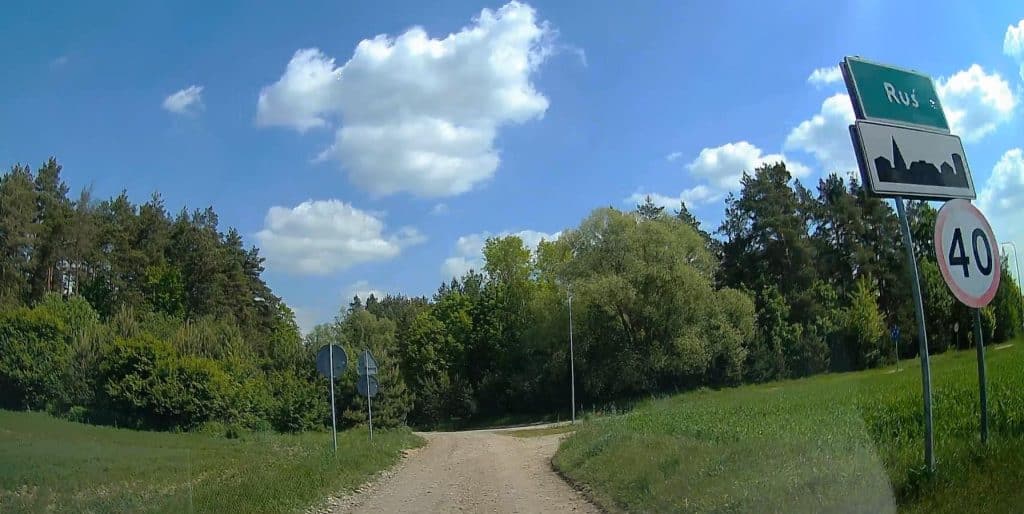 Droga powiatowa w miejscowości Ruś, zakończona modernizacja, widok na odcinek z zielonymi drzewami i niebieskim niebem.