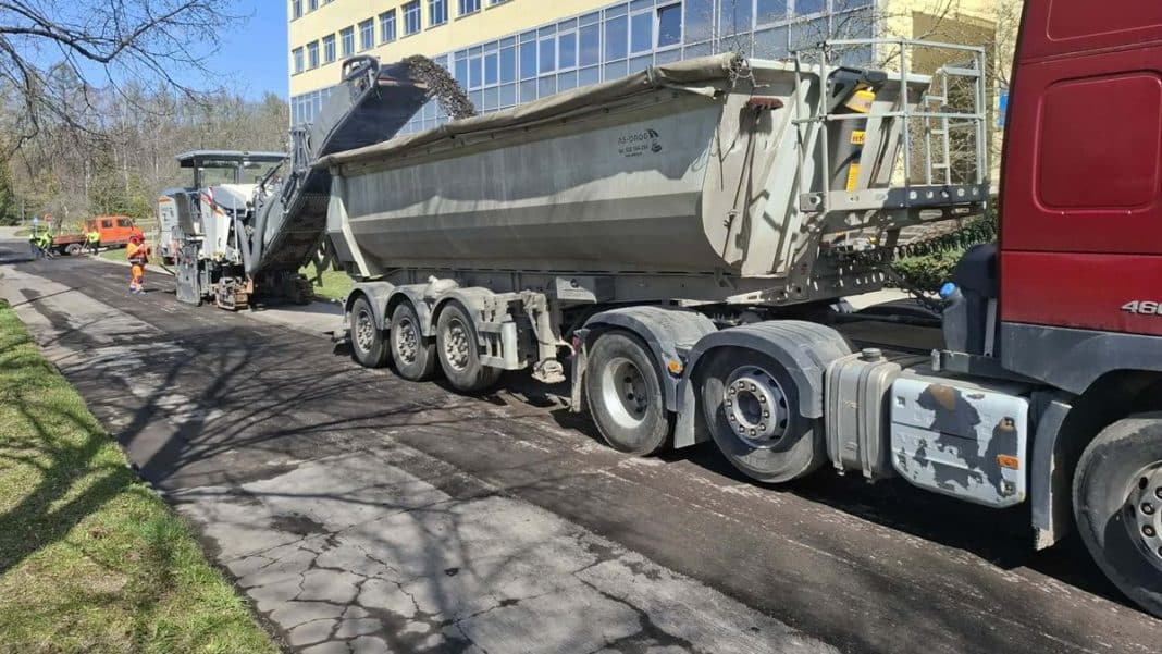 Prace remontowe na ulicy Kurta Obitza w Olsztynie, widok na ciężar&oacute;wkę i roboty drogowe.