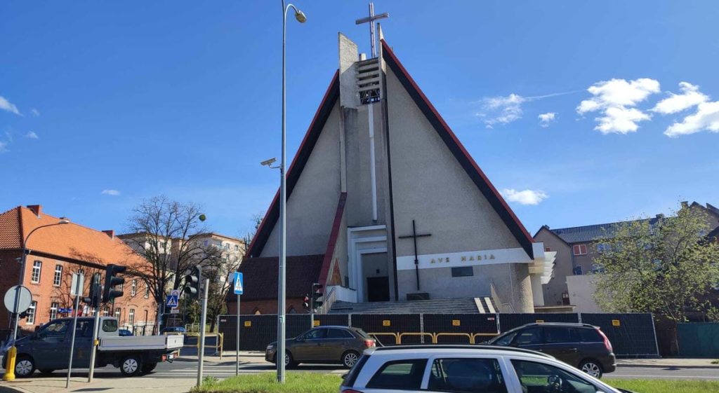Kości&oacute;ł w Olsztynie na Jarotach z rozpoczętymi pracami remontowymi, ogrodzony teren i zabezpieczone wejście.