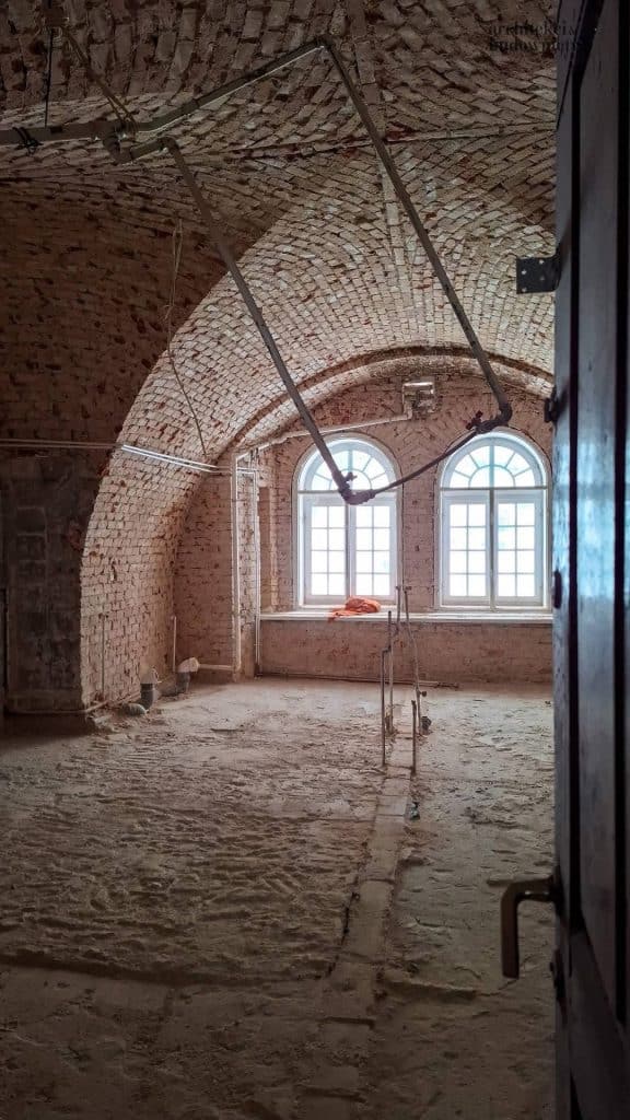 Widok wnętrza odrestaurowanego koszarowca w Twierdzy Boyen, z ceglaną sklepioną architekturą i oknami.