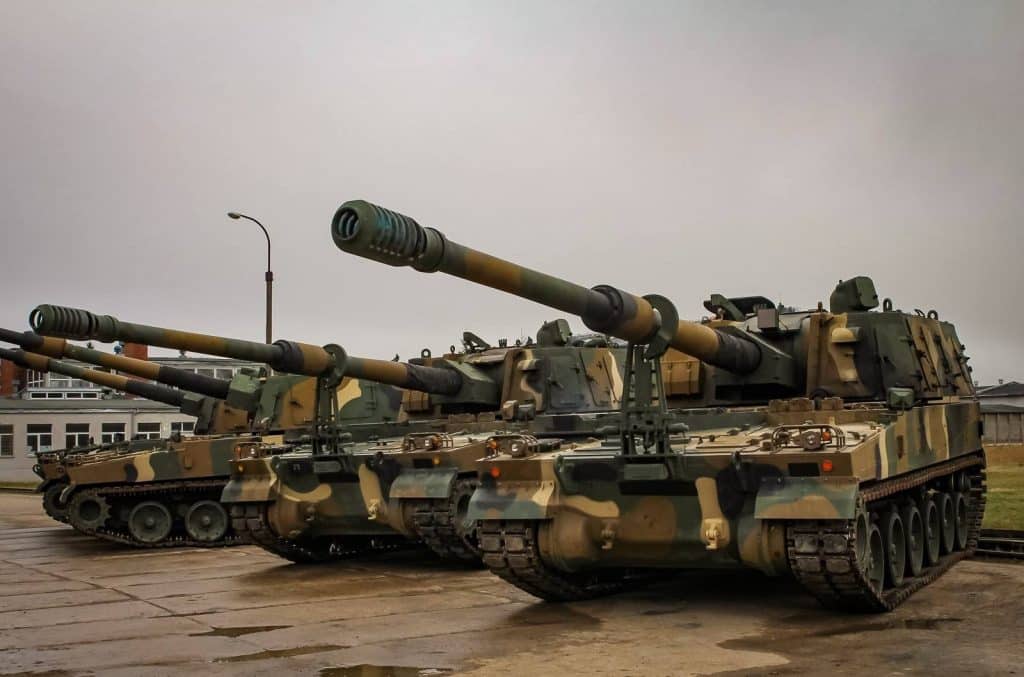 Dwa czołgi z zamontowanymi armatami na placu, w pochmurny dzień.