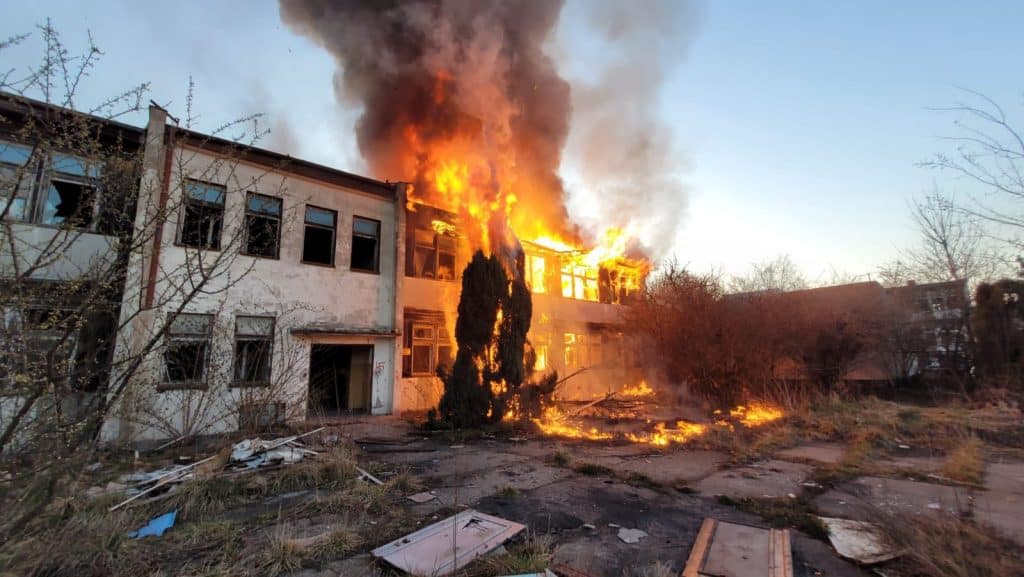 Pożar pustostanu przy ul. Junak&oacute;w w Elblągu, płomienie i dym unoszą się nad budynkiem.