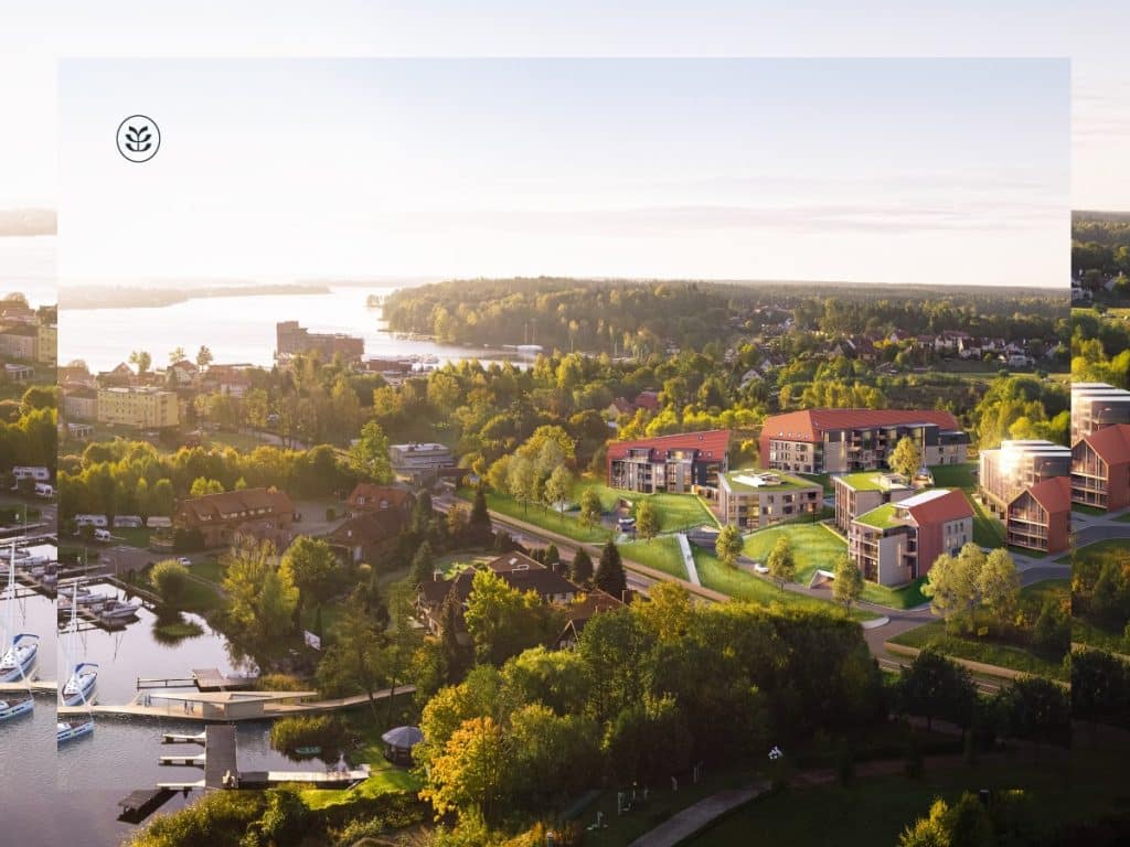 Widok na nowoczesne apartamenty nad jeziorem w Mikołajkach, otoczone zielenią i mariną.