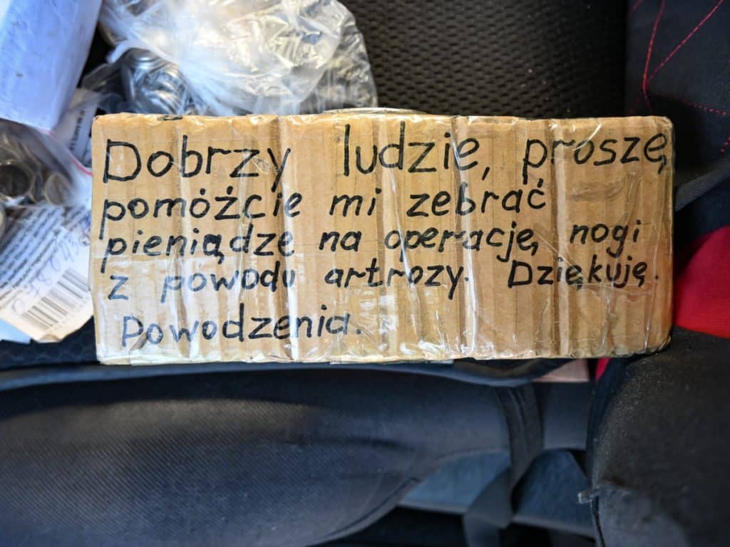 Kartka z prośbą o pomoc finansową na operację, napisana ręcznie na kawałku kartonu.