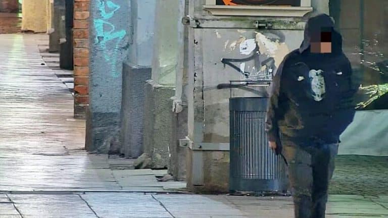 Mężczyzna w kapturze z nożem na Starym Mieście w Olsztynie, patrol służb w tle.