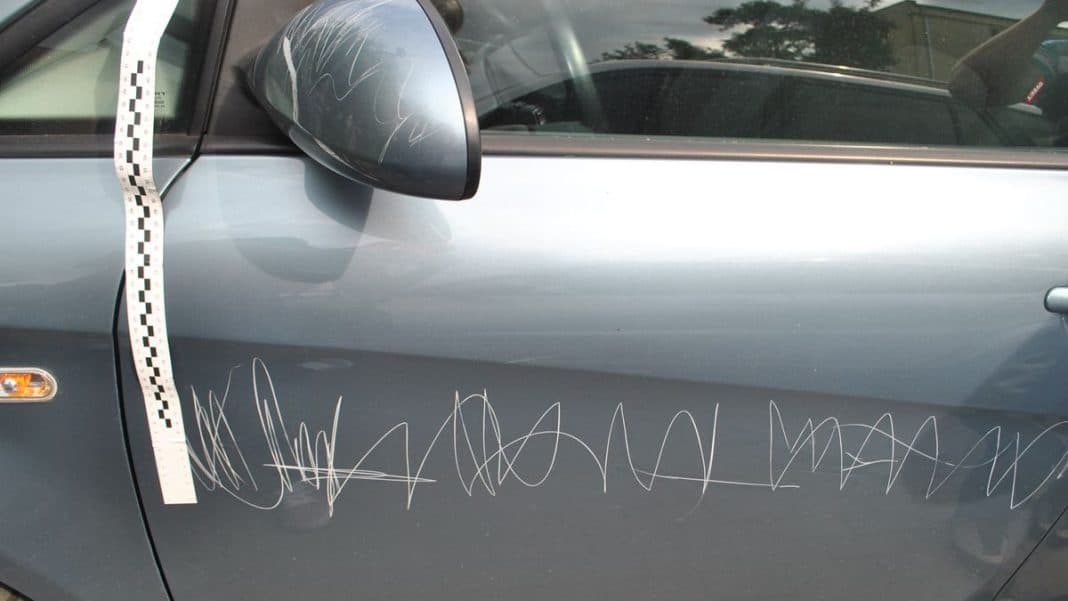 Samoch&oacute;d zarysowany ostrym narzędziem, widoczny na zdjęciu, z licznymi rysami na drzwiach.