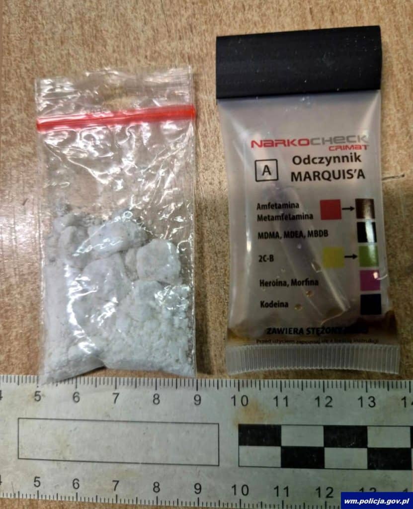 Zdjęcie narkotyk&oacute;w i listu gończego na stole, obok miarka i skal&oacute;wka.