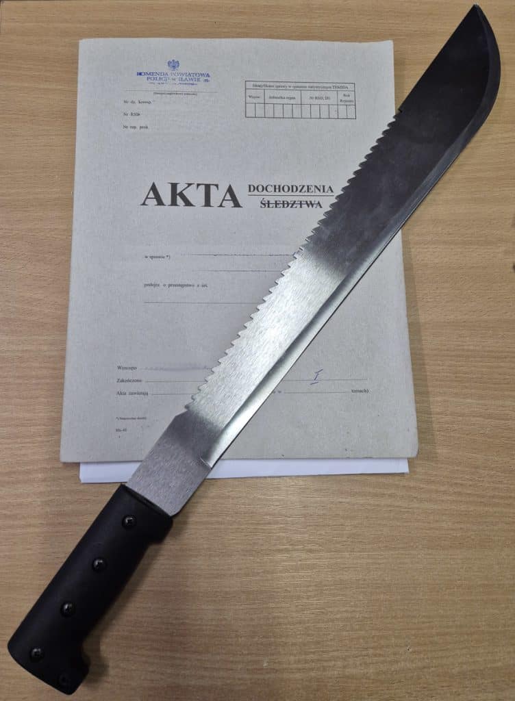 N&oacute;ż leżący na akcie dochodzenia, obok dokumentu policyjnego, na drewnianym stole.