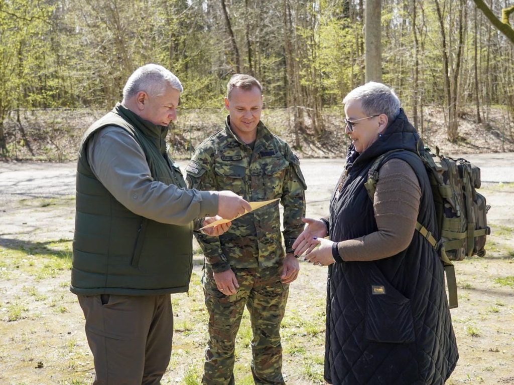 Grupa os&oacute;b sadzących drzewa w lesie, w tle drzewa i wiosenna przyroda.