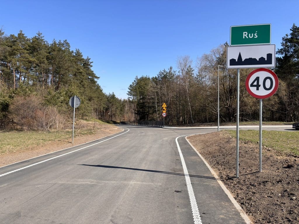 Nowa, wyremontowana droga w miejscowości Ruś, z oznakowaniem ograniczenia prędkości 40 km/h, otoczona lasem.