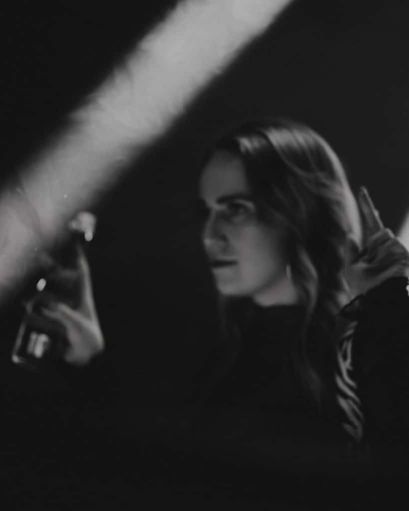 Kobieta patrzy na osobę z mikrofonem podczas imprezy w klubie, w ciemnym otoczeniu, w czerni i bieli.