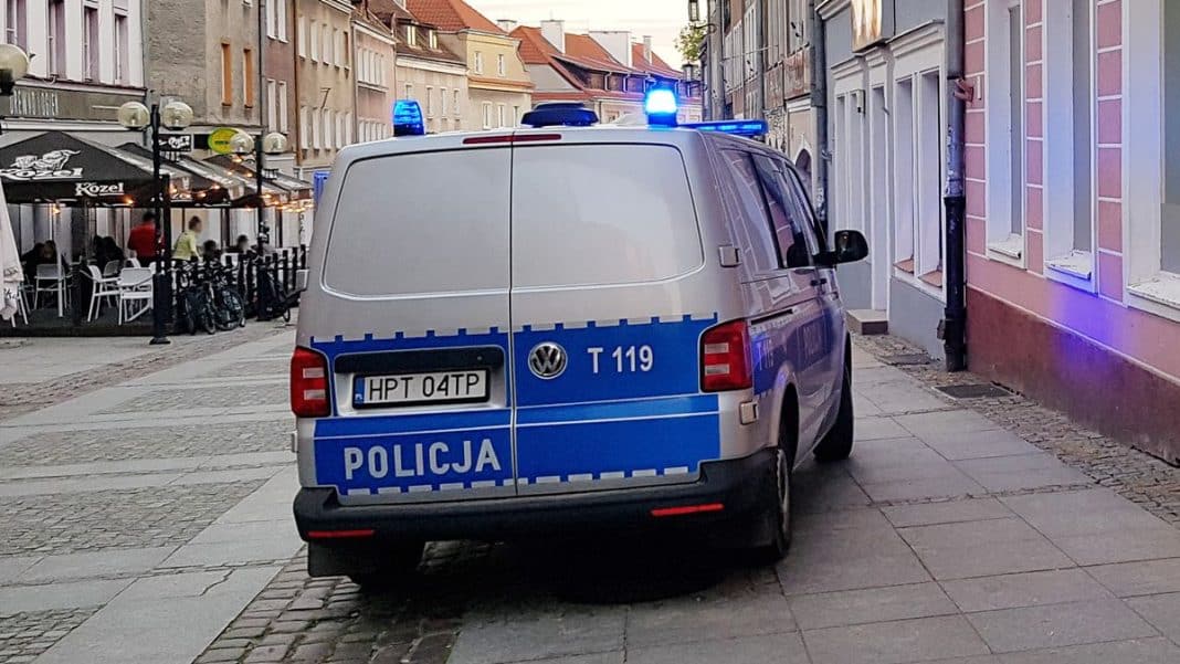 Policja zatrzymała poszukiwanego mężczyznę na ulicy w Olsztynie, na tle budynk&oacute;w i restauracji.