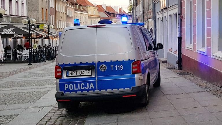 Policja zatrzymała poszukiwanego mężczyznę na ulicy w Olsztynie, na tle budynk&oacute;w i restauracji.