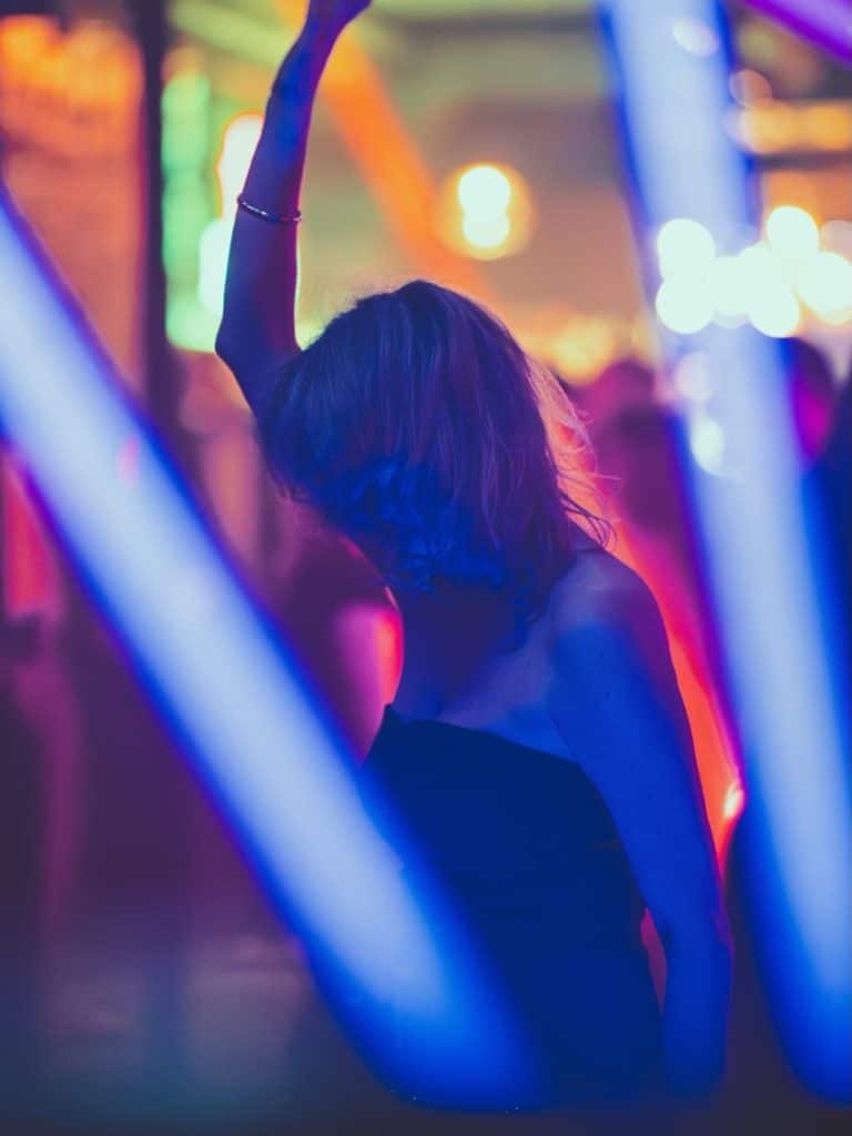 Tancerka na parkiecie w klubie z kolorowym oświetleniem, w ruchu podczas imprezy.