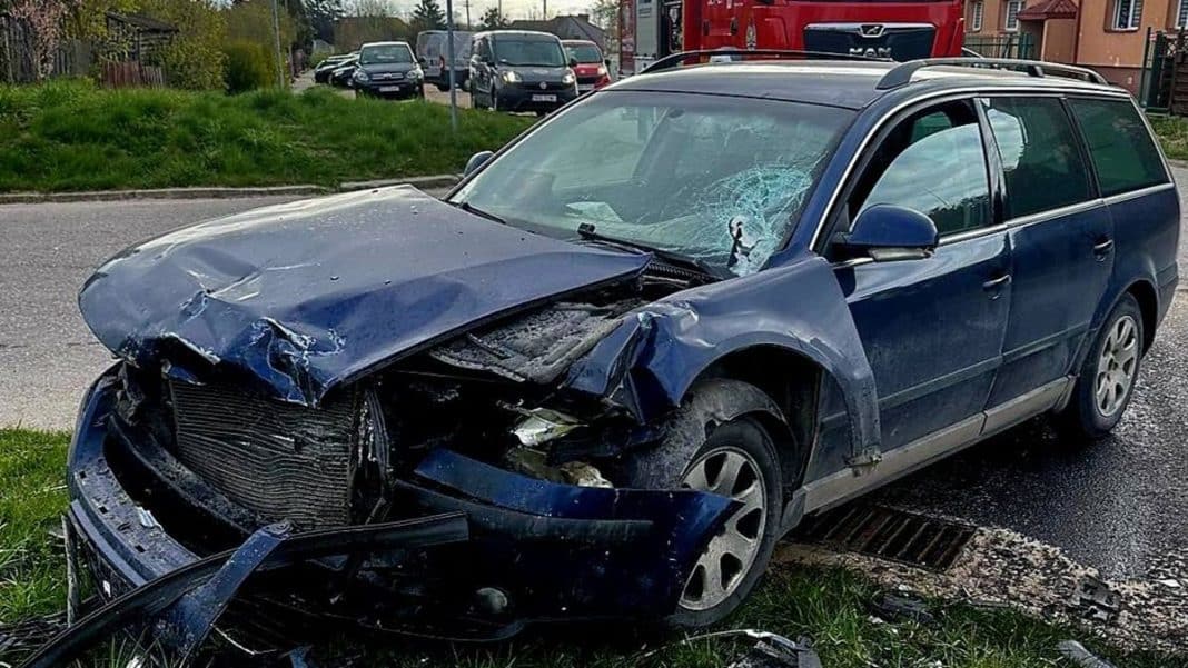 Uszkodzony samoch&oacute;d marki Volkswagen po kolizji, z rozbitym przodem i wybitym szybą przednią.