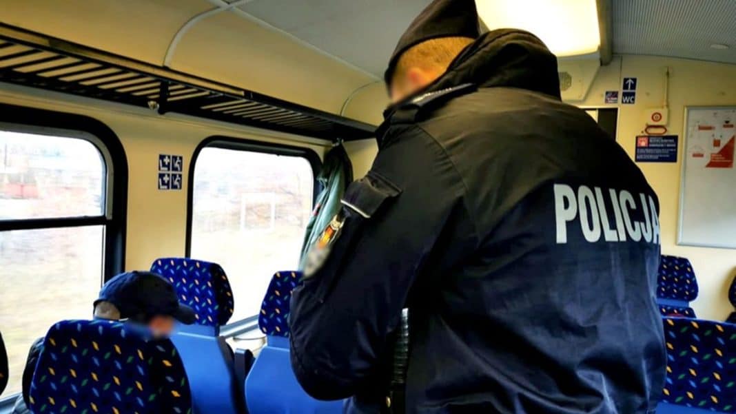 Policjant w uniformie na pokładzie pociągu relacji Olsztyn&ndash;Morąg, rozmawiający z pasażerem.