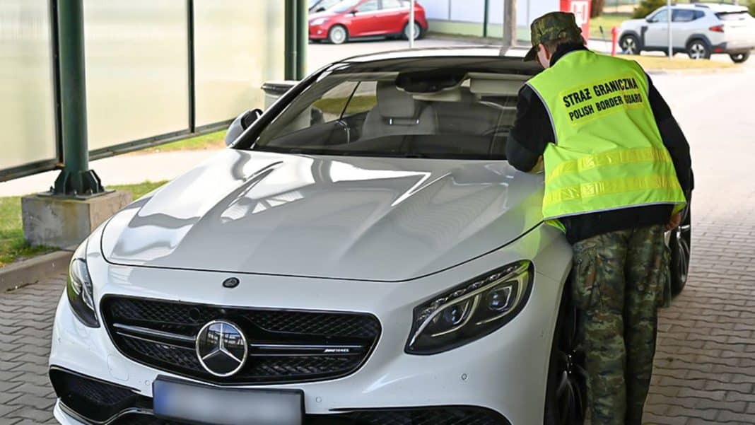 Funkcjonariusz Straży Granicznej kontroluje luksusowy samoch&oacute;d na przejściu granicznym.